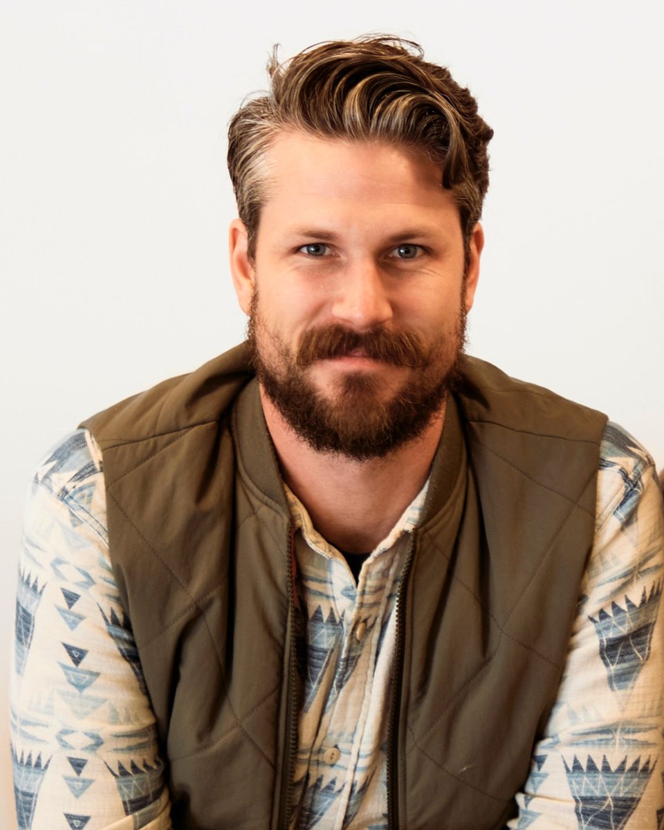 Curtis Rempel, smiling, in an olive vest and patterned shirt